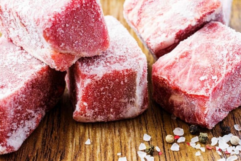 Cinq morceaux de viande congelée présentés sur une planche en bois avec glace, cristaux de sel et poivre